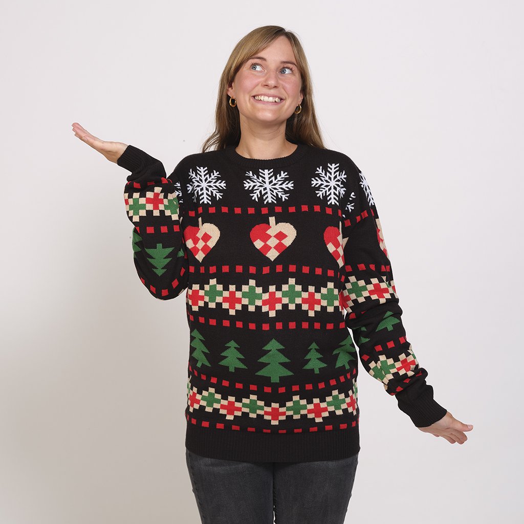 Une femme portant un pull de Noël noir avec un imprimé de Noël.